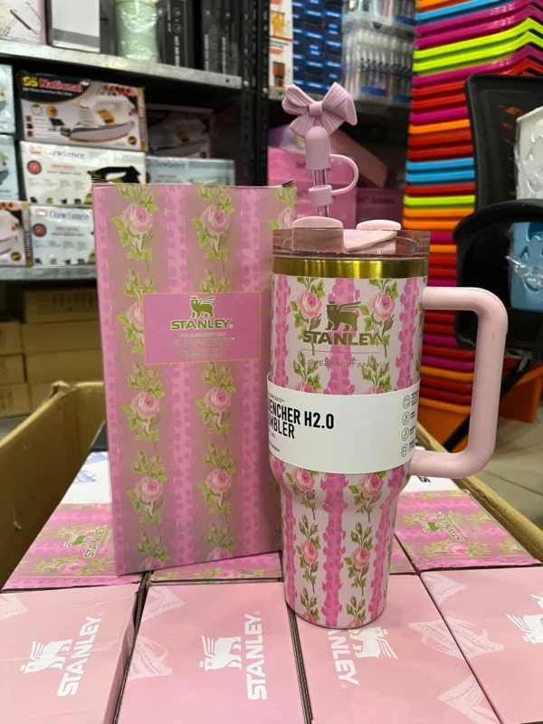 Pink floral insulated tumbler with a handle and straw lid in front of its box