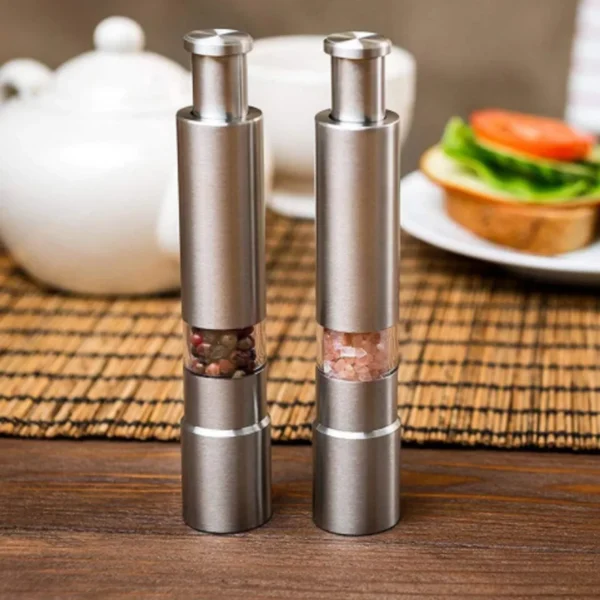 Stainless steel push-button spice grinders with clear windows showing peppercorns and salt