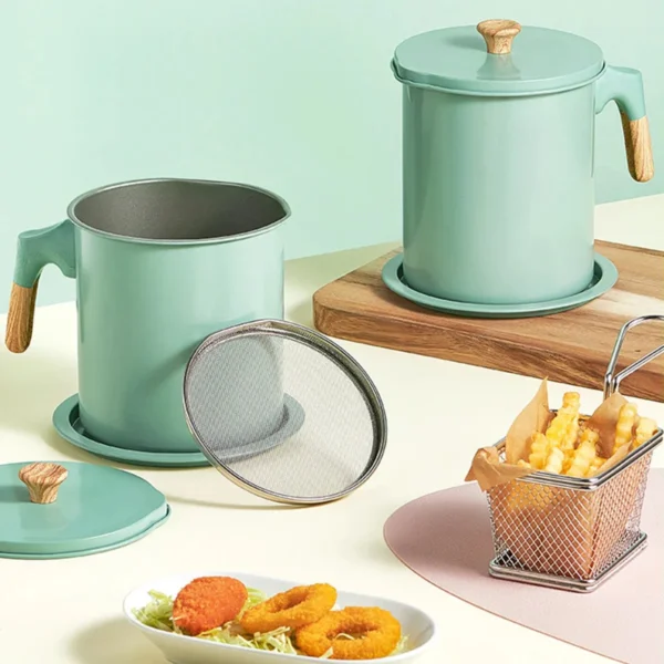 Two mint green oil pots with lids and a removable mesh filter beside fried snacks