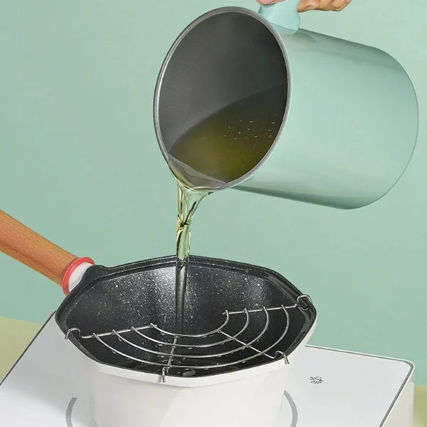 Oil being poured from the mint green pot into a frying pan