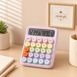 Pink pastel calculator with round coloured keys on a desk beside a small plant