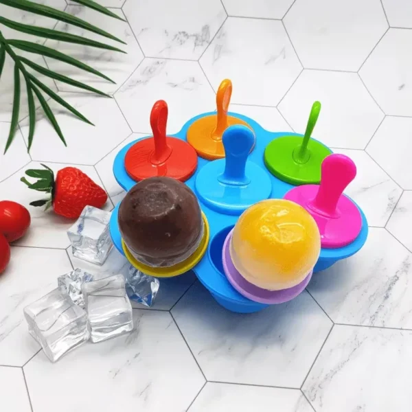Silicone popsicle mold with chocolate and fruit treats and ice cubes on a tile surface