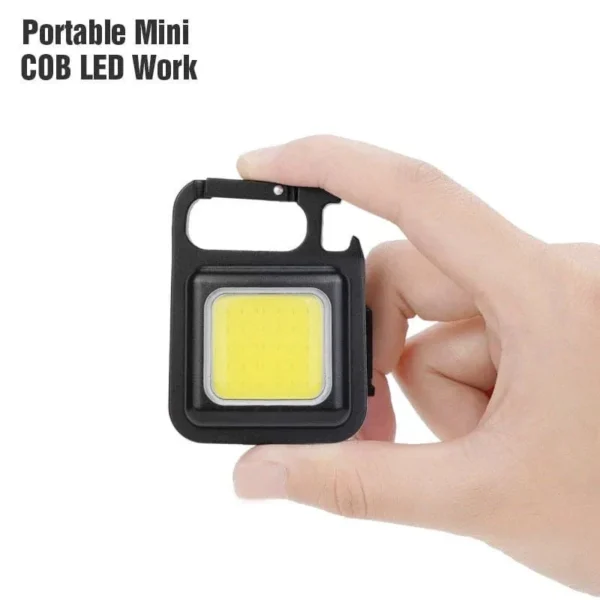 Hand holding the small square mini LED flashlight keychain with its carabiner loop