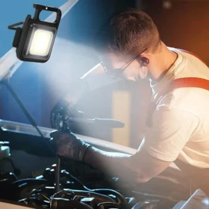 Mini LED flashlight keychain lighting the engine bay while a man works on a car