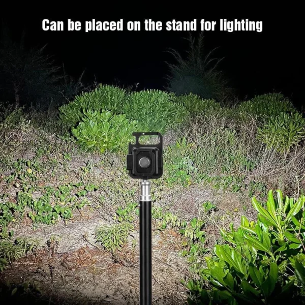 Mini LED flashlight keychain mounted on a thin stand, lighting up bushes outdoors at night