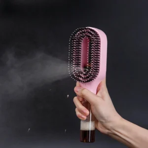 Pink 2-in-1 spray hair brush with a clear bottle handle spraying a fine water mist