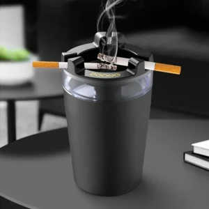 Black cup-shaped ashtray with two cigarettes resting on its notched top ring on a table