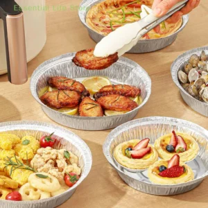 Round foil plates holding grilled meat, seafood and tarts on a table