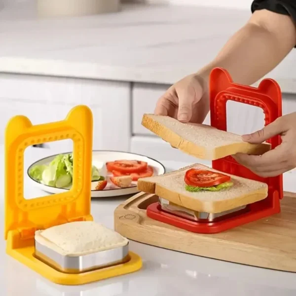 Hands filling a sandwich with tomato and lettuce on a red hinged sandwich cutter and sealer, with a yellow one beside it