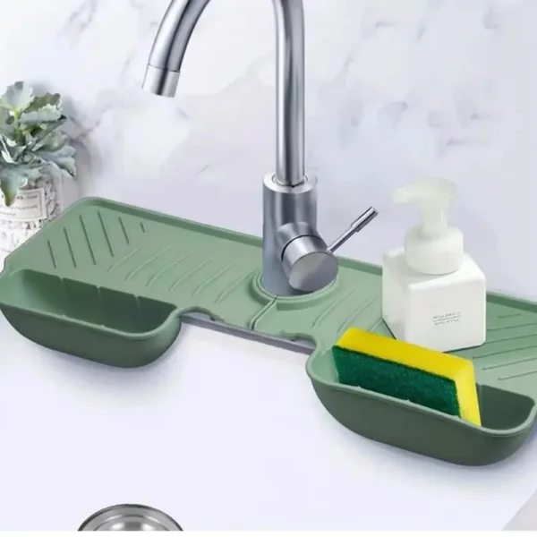 Green silicone faucet tray with a sponge in one basket and a soap bottle beside the tap