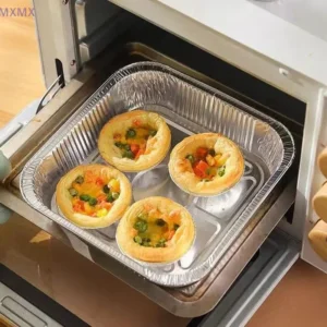Square foil plate holding small baked tartlets inside an oven