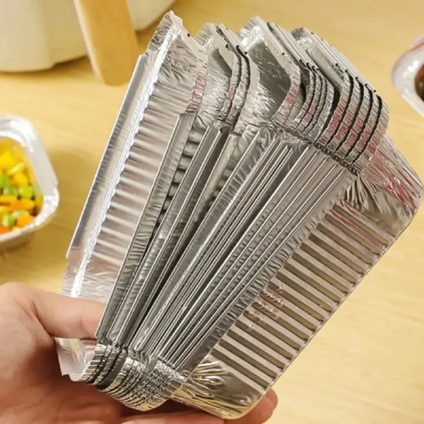 Side view of stacked square foil plates held in a hand