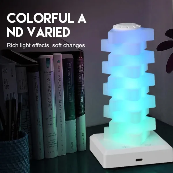 Colourful stacked cube lamp on a white base beside books