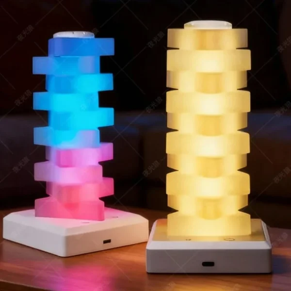 Two stacked lamps, one glowing pink and blue and one in warm yellow light