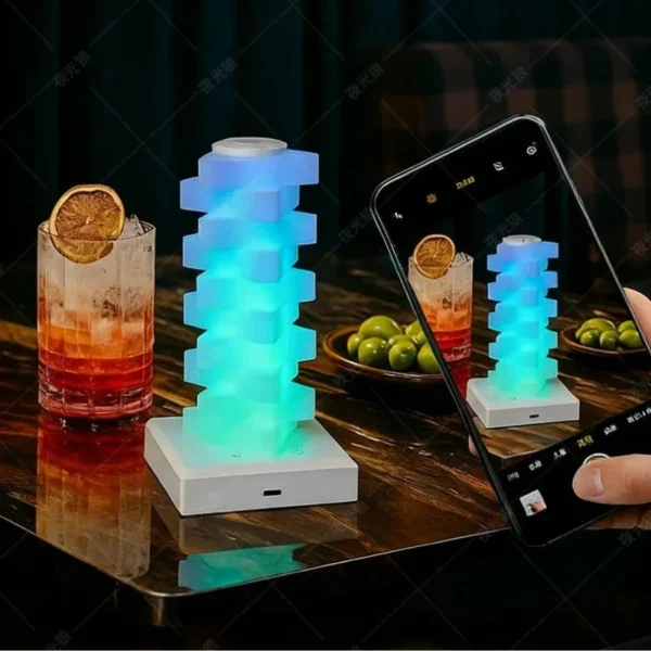 Blue glowing stacked lamp on a table next to drinks and a phone