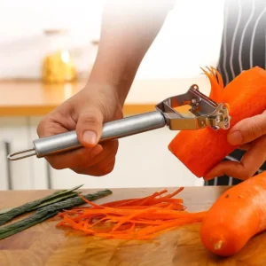 Stainless steel vegetable peeler making thin julienne strips from a carrot