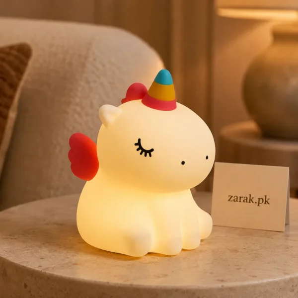 Glowing unicorn silicone night light on a side table beside a cushion